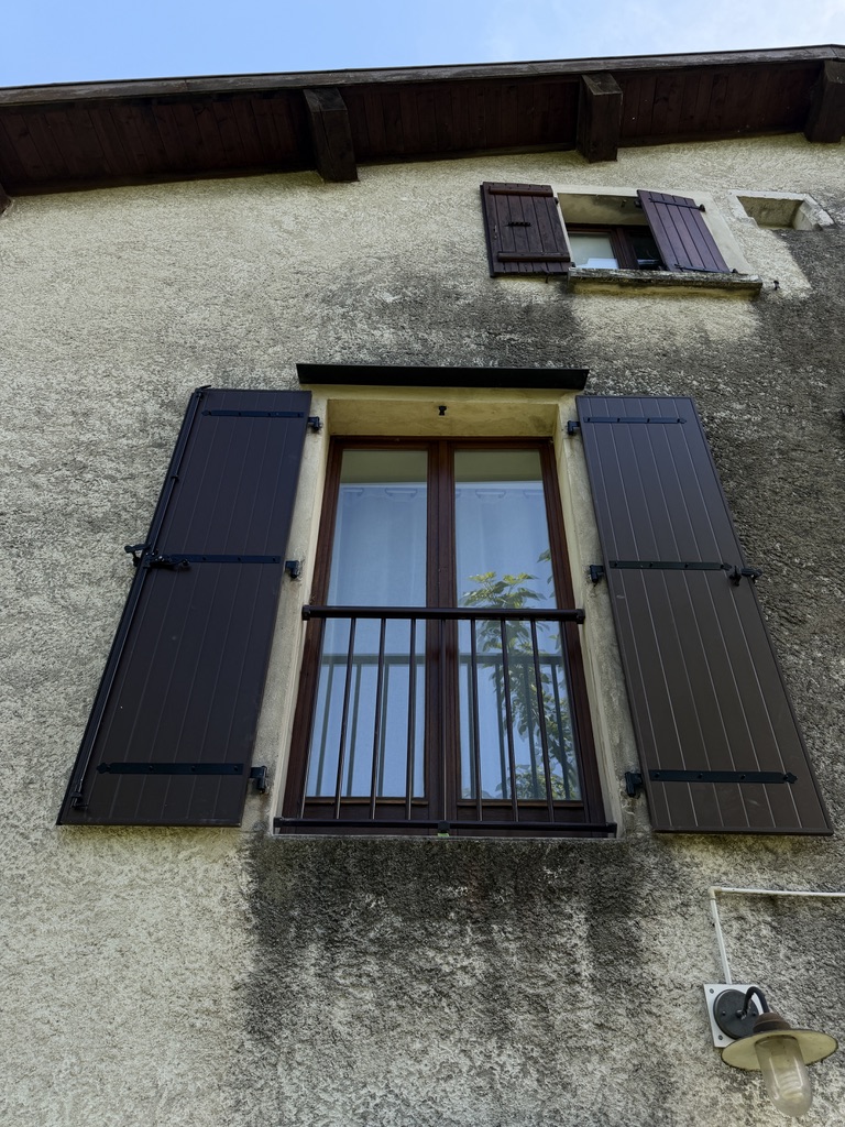 Volets en bois et garde-corps métalliques rénovés avec une peinture neuve et une finition soignée.